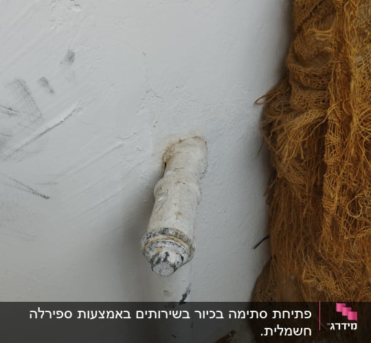 צינור מים לבן עם סימני שחיקה על הקיר